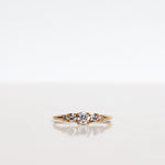 Mumbaistockholm Fine Jewelry Ring: Elise Ring in 18K yellow gold with five white, conflict-free diamonds. The center diamond is 0.25 CT, and on each side are two 0.11 CT diamonds, and two 0.04 CT diamonds. Pictured from the front.