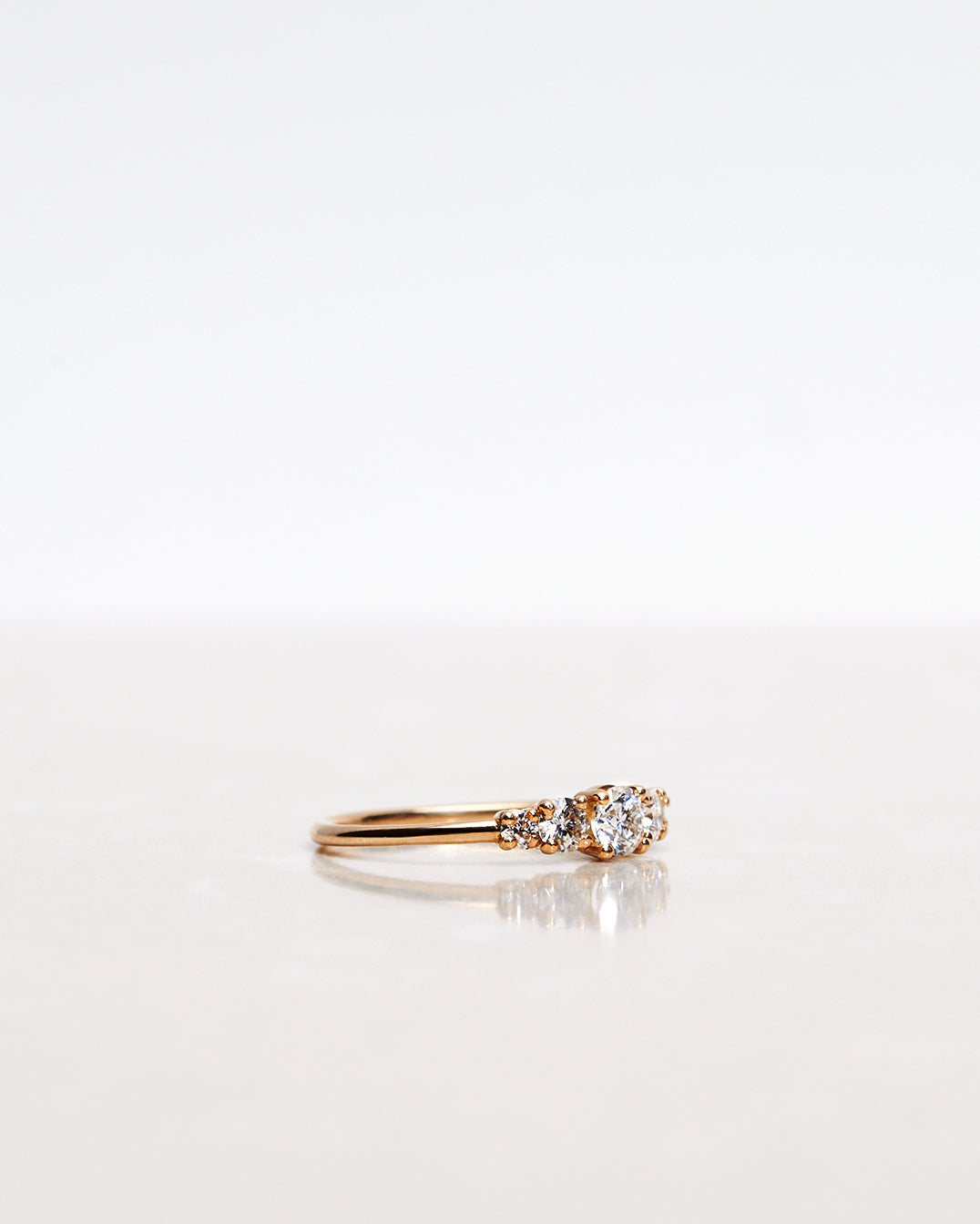 Mumbaistockholm Fine Jewelry Ring: Elise Ring in 18K yellow gold with five white, conflict-free diamonds. The center diamond is 0.25 CT, and on each side are two 0.11 CT diamonds, and two 0.04 CT diamonds. Pictured from the side.